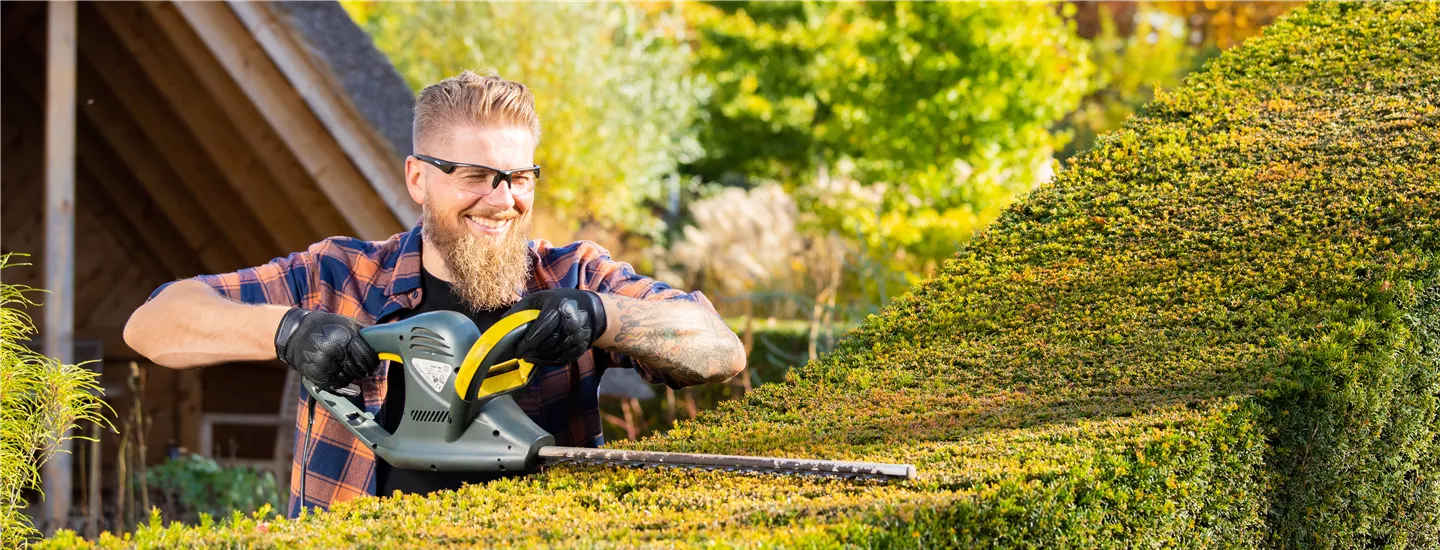 Gartengeräte - Mann mit elektrischer Heckenschere